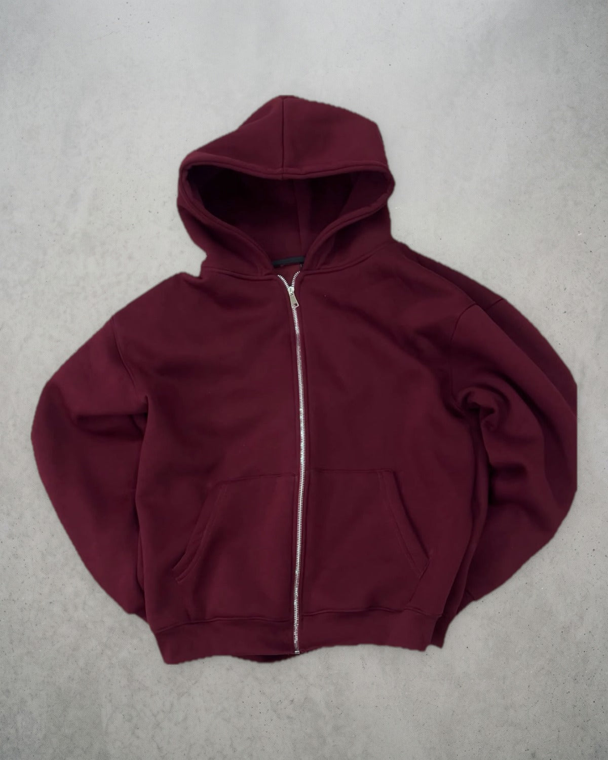 Zip-up bordeaux posé à plat sur un sol en béton, vue de face