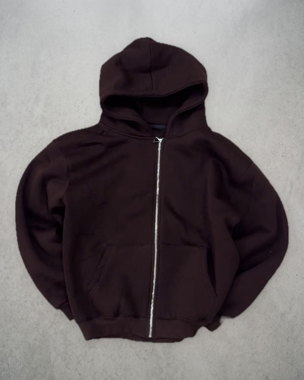 Zip-up chocolat posé à plat sur un sol en béton, vue de face